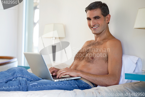 Image of Shirtless Man Working on Laptop