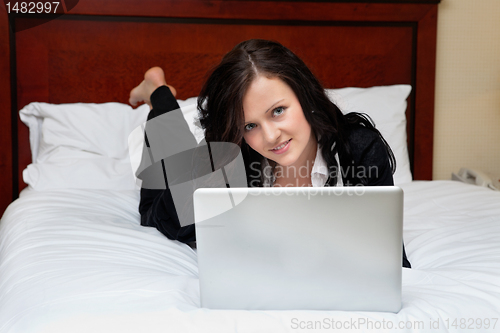 Image of Female Executive Lying on Bed With Laptop