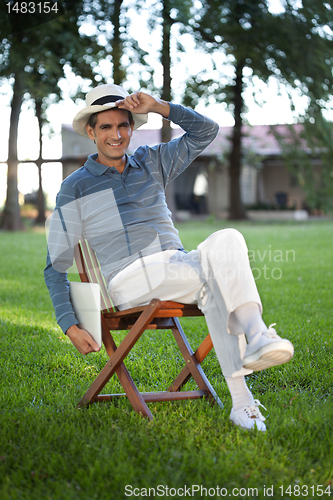 Image of Casual Man Sitting in Park Holding Tablet PC