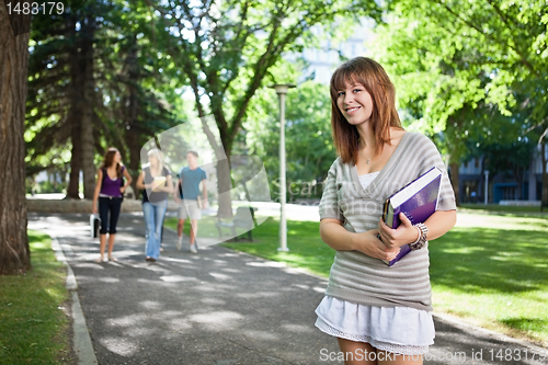 Image of College girl standing with a book