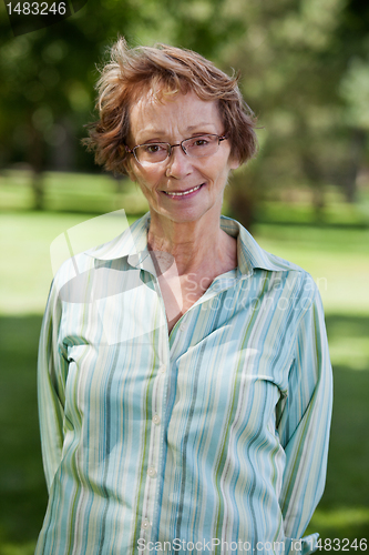 Image of Happy senior woman standing in park