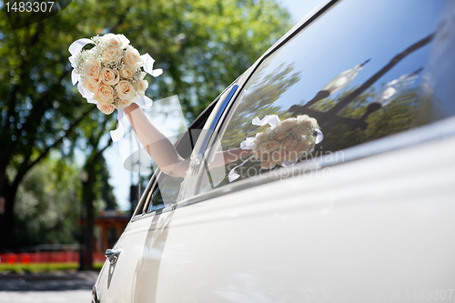 Image of Bride waving hand holding bouquet