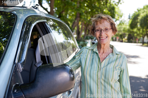 Image of Senior woman standing near car