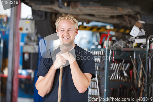 Image of Smiling mechanic holding broom