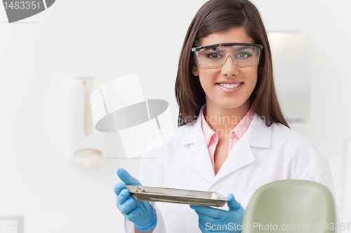 Image of Dentist holding tray of dental instruments