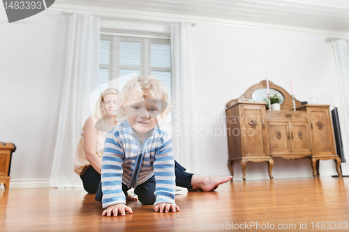 Image of Baby crawling with mother in the background
