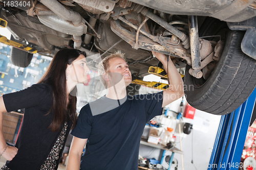 Image of Woman and mechanic looking at car repairs