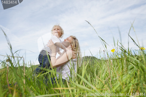 Image of Mother sitting on grass while playing with boy