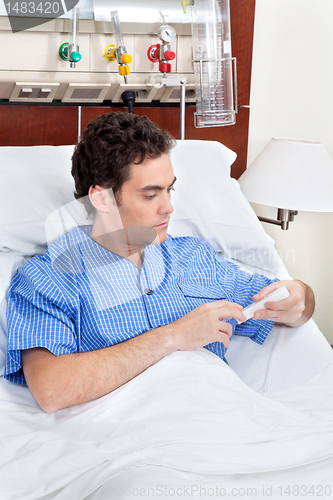 Image of Patient sitting on bed reading medicine box