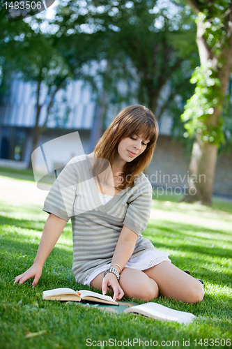 Image of Young girl sitting down on grass with books