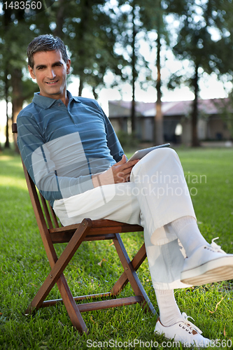 Image of Casual Man Sitting in Park With Tablet PC