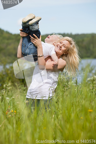 Image of Smiling mother playing with child