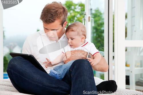 Image of Man Using Digital Tablet while Holding Child