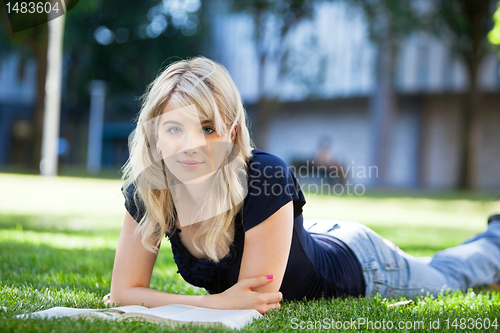 Image of Girl lying on grass with a book