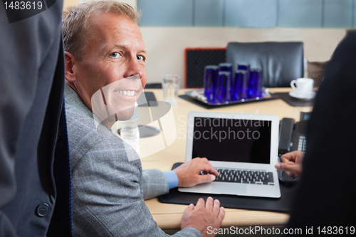 Image of Mature man using laptop in office