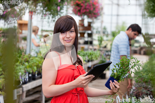 Image of Woman with tablet pc and potted plant