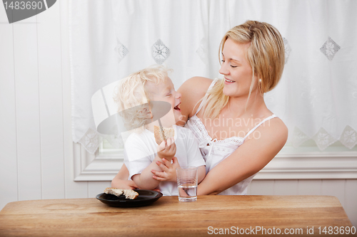 Image of Mother looking at boy eating bread