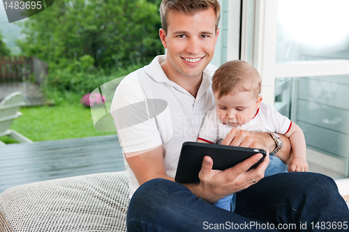 Image of Man using digital tablet with child