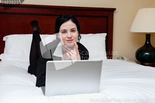 Image of Female Executive Lying on Bed With Laptop