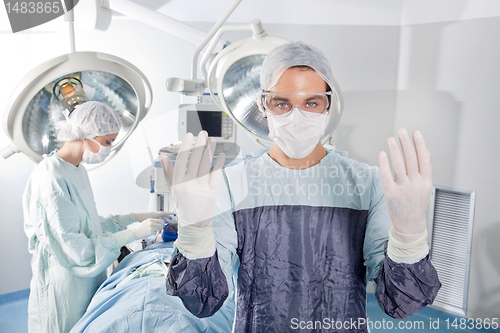 Image of Male surgeon asking for gloves