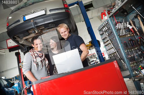 Image of Couple in auto repair shop standing with mechanic