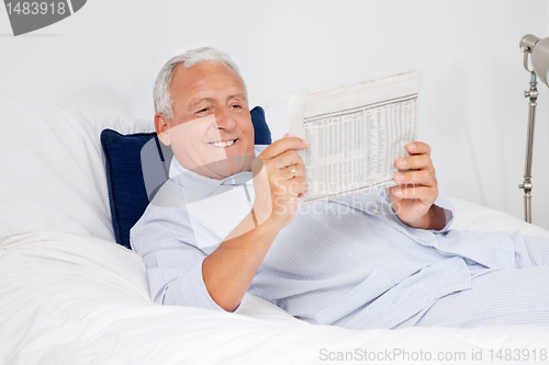 Image of Relaxed Senior Man Reading Newspaper