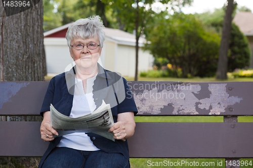 Image of Senior Woman Reading Newspaper in Park