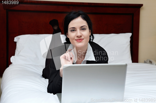 Image of Smiling Businesswoman Lying on Bed With Laptop