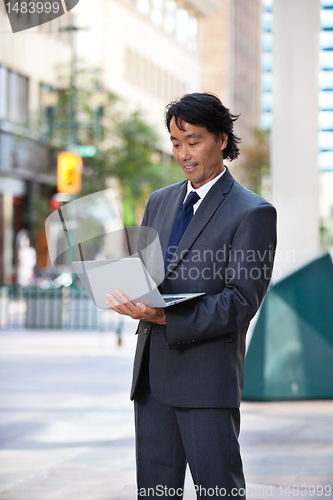Image of Smiling businessman using laptop
