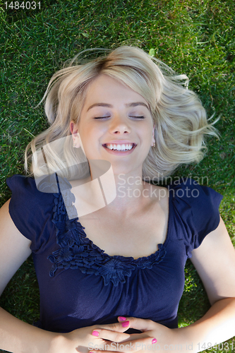 Image of Happy young woman lying on grass