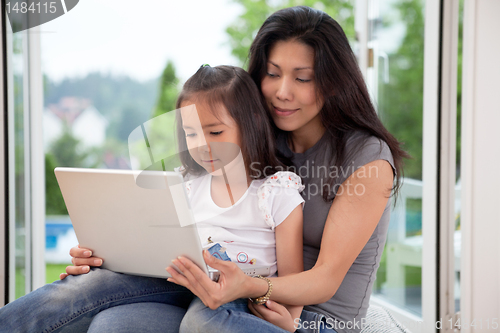Image of Cute daughter and mother with laptop