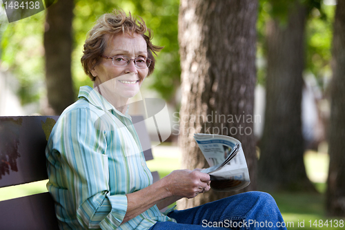 Image of Woman reading newspaper in park