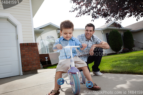 Image of Father teaching Son To Ride a Tricycle