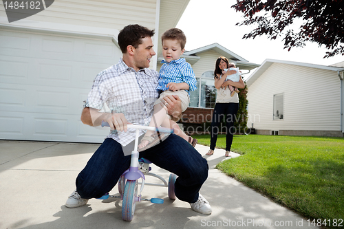 Image of Playful Father Sitting on Tricycle With Son