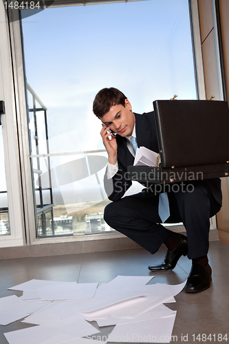 Image of Man Bending Down to Collect Scattered Papers
