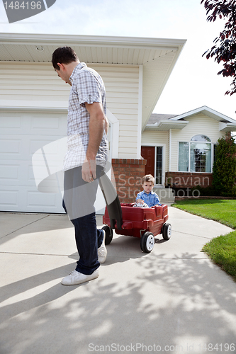 Image of Father Pulling Son Sitting in Wagon