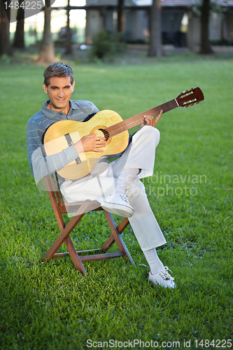 Image of Man Playing Guitar Sitting in Lawn