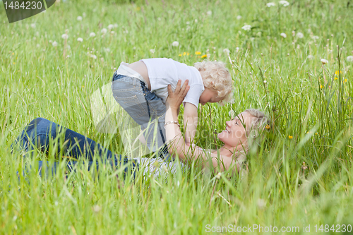 Image of Mother lying on grass and playing with son
