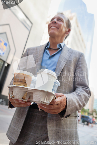 Image of Businessman carrying takeaway cups