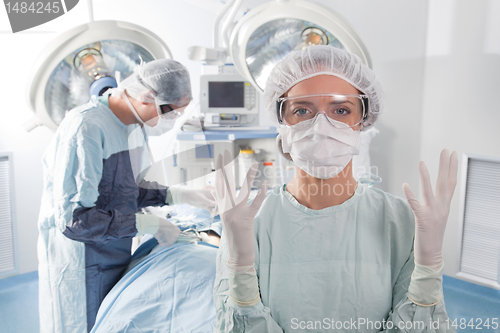 Image of Female surgeon asking for gloves