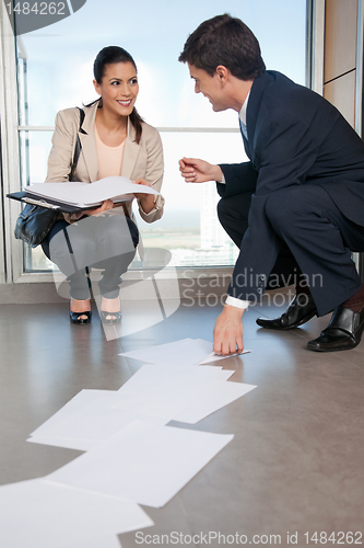 Image of Man Helping Woman Collect Fallen Documents