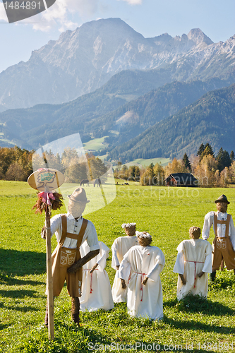 Image of Group of scarecrows in female dress standing on a field