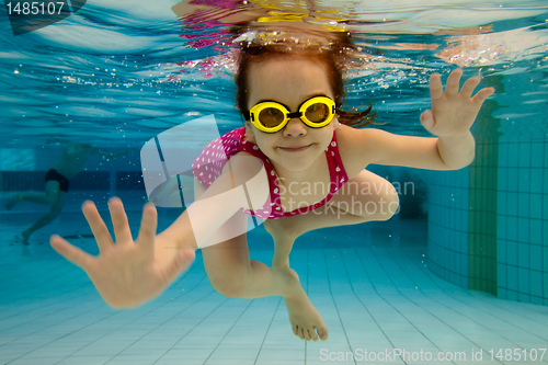 Image of The girl smiles, swimming under water in the pool