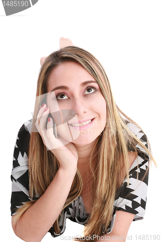 Image of Jolly woman talking on phone lying on a bed at home 