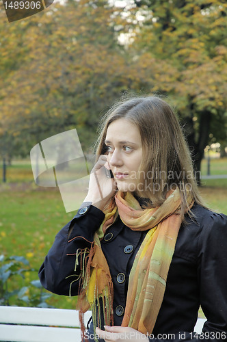 Image of woman is talking on the phone in an autumnal Park 