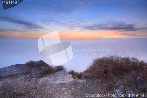 Image of dark landscape with fog between hills and orange sky before sunr