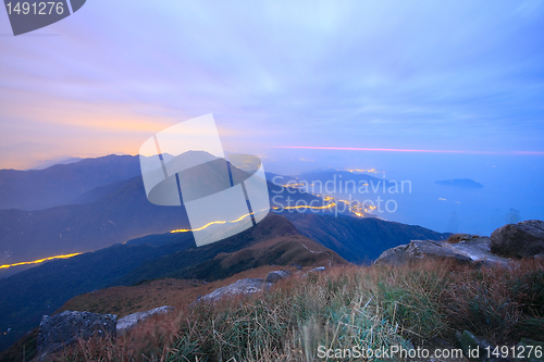 Image of dark landscape with fog between hills and orange sky before sunr