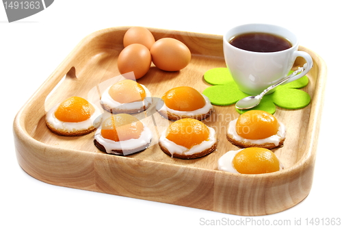 Image of Easter biscuits and a cup of tea on wooden tray.