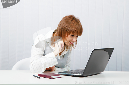 Image of Attractive smiling girl with a laptop in the office