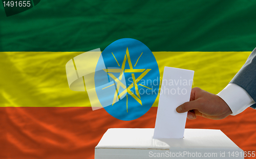 Image of man voting on elections in ethiopia in front of flag